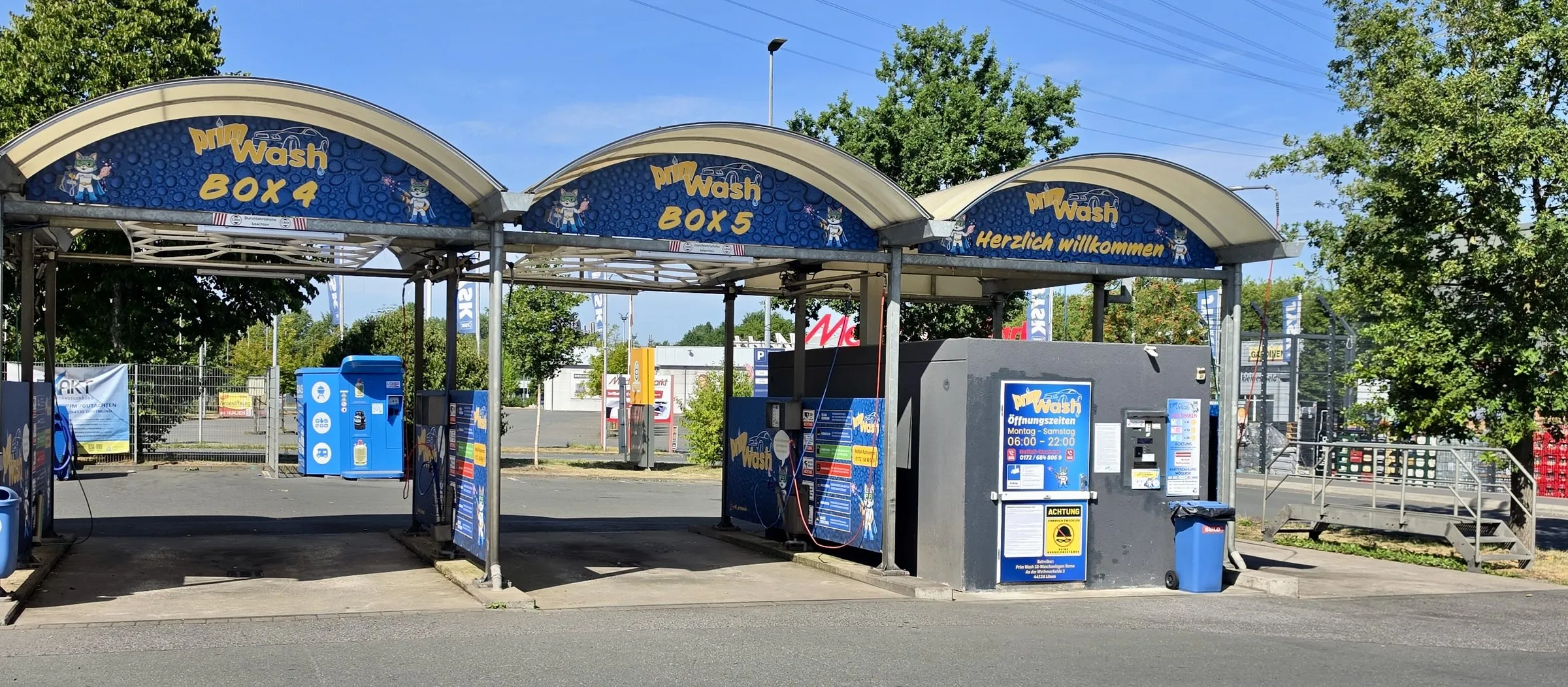 Waschboxen 4 und 5 in Castrop-Rauxel, daneben der Willkommensbogen über dem Technikgebäude mit Öffnungszeiten-Schild