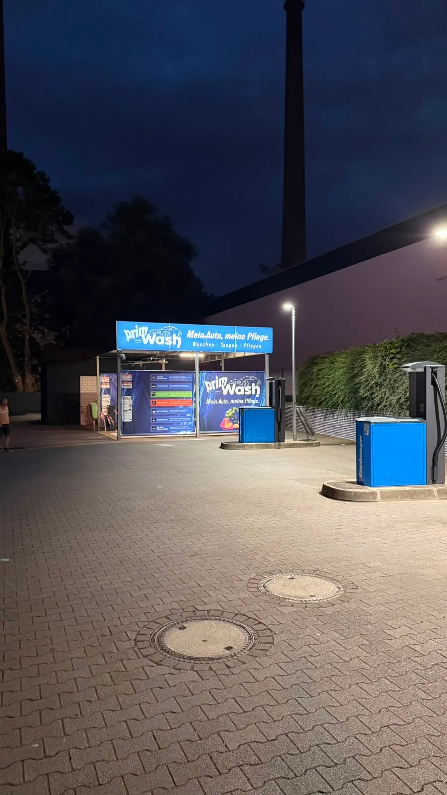 Beleuchtete Prim Wash Einfahrt an der Gladbecker Straße in der Abenddämmerung, daneben die blauen Sauger-Stationen