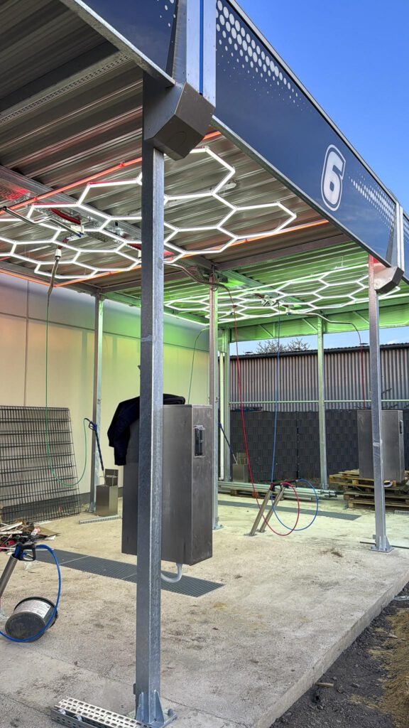 Prim_Wash_Baustelle-28 Mehrere SB-Waschboxen mit leuchtenden LED-Paneelen in blauem Licht bei Bauabschluss