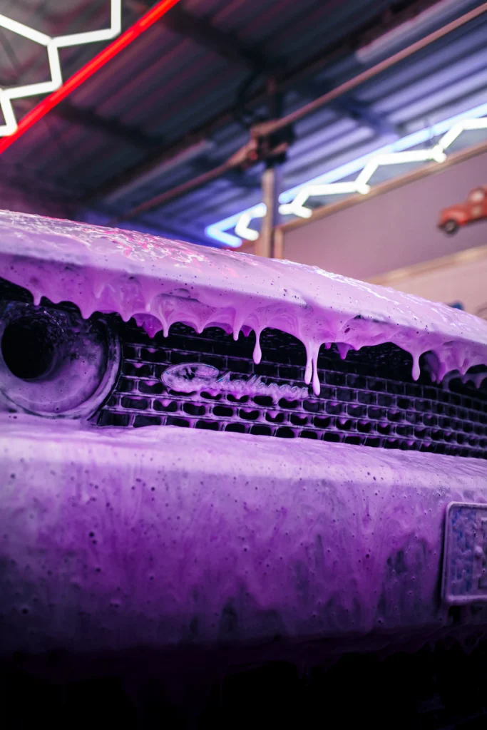 Nahaufnahme eines Autos mit pinken Powerschaum in der SB-Waschanlage – intensiver Reinigungsschaum von Prim Wash für perfekte Fahrzeugpflege